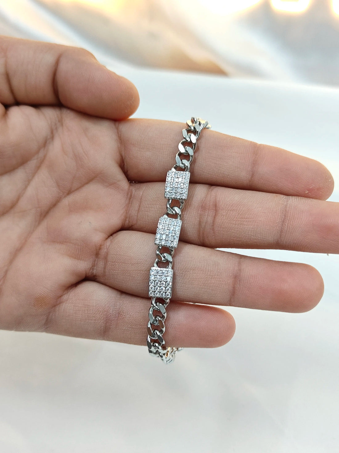 Silver bracelet with diamond accents on a hand against a neutral background