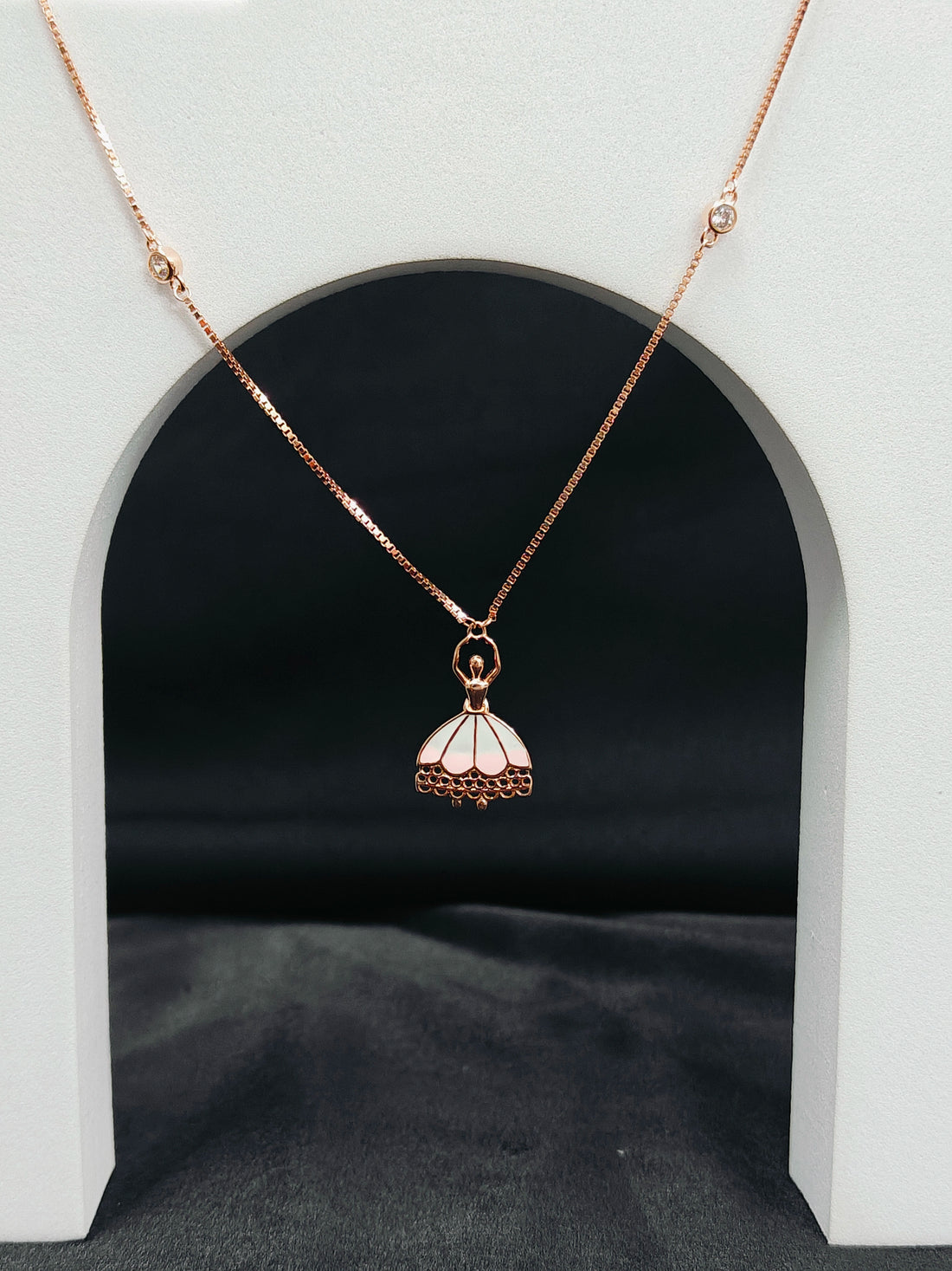 Rose gold necklace with a pendant on a white archway background