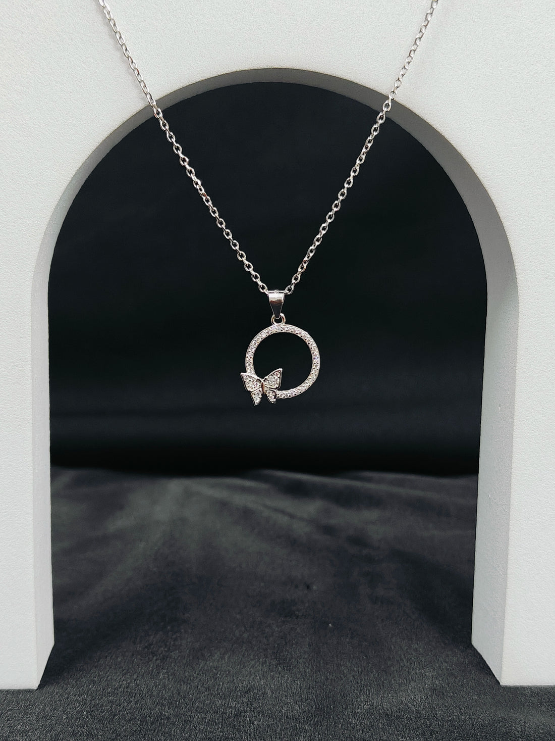 Silver necklace with a butterfly pendant on a dark background