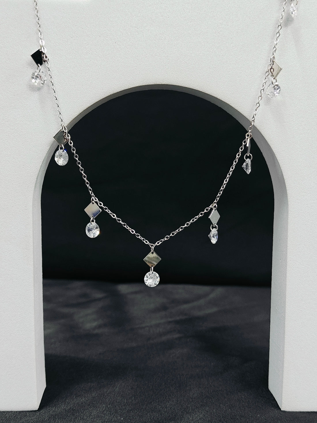 Silver necklace with pendant on a white arch background