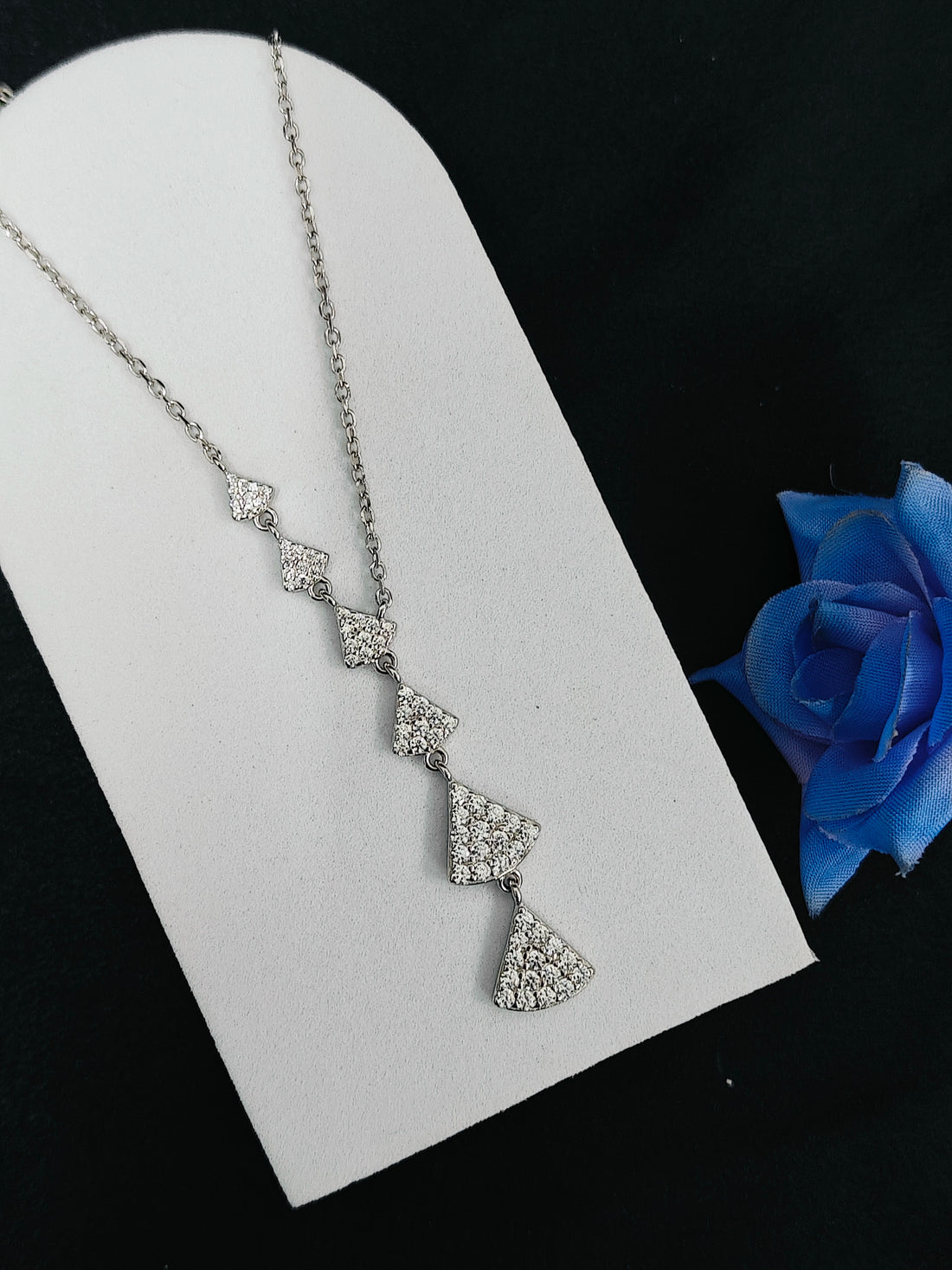 Silver necklace with a blue rose on a black background