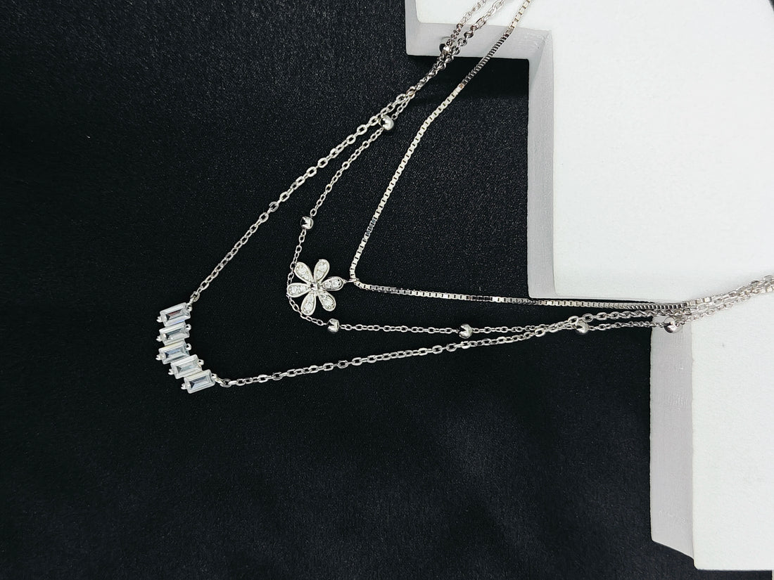 Silver necklace with floral pendant on a black background