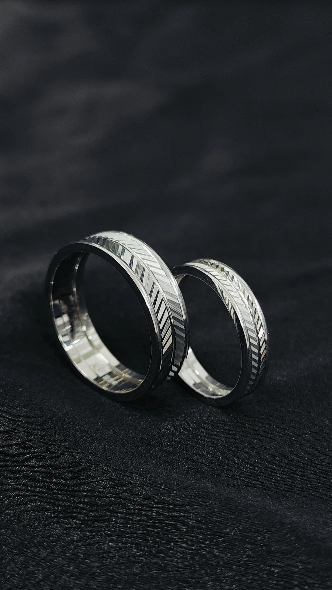 Two silver rings with intricate designs on a dark background
