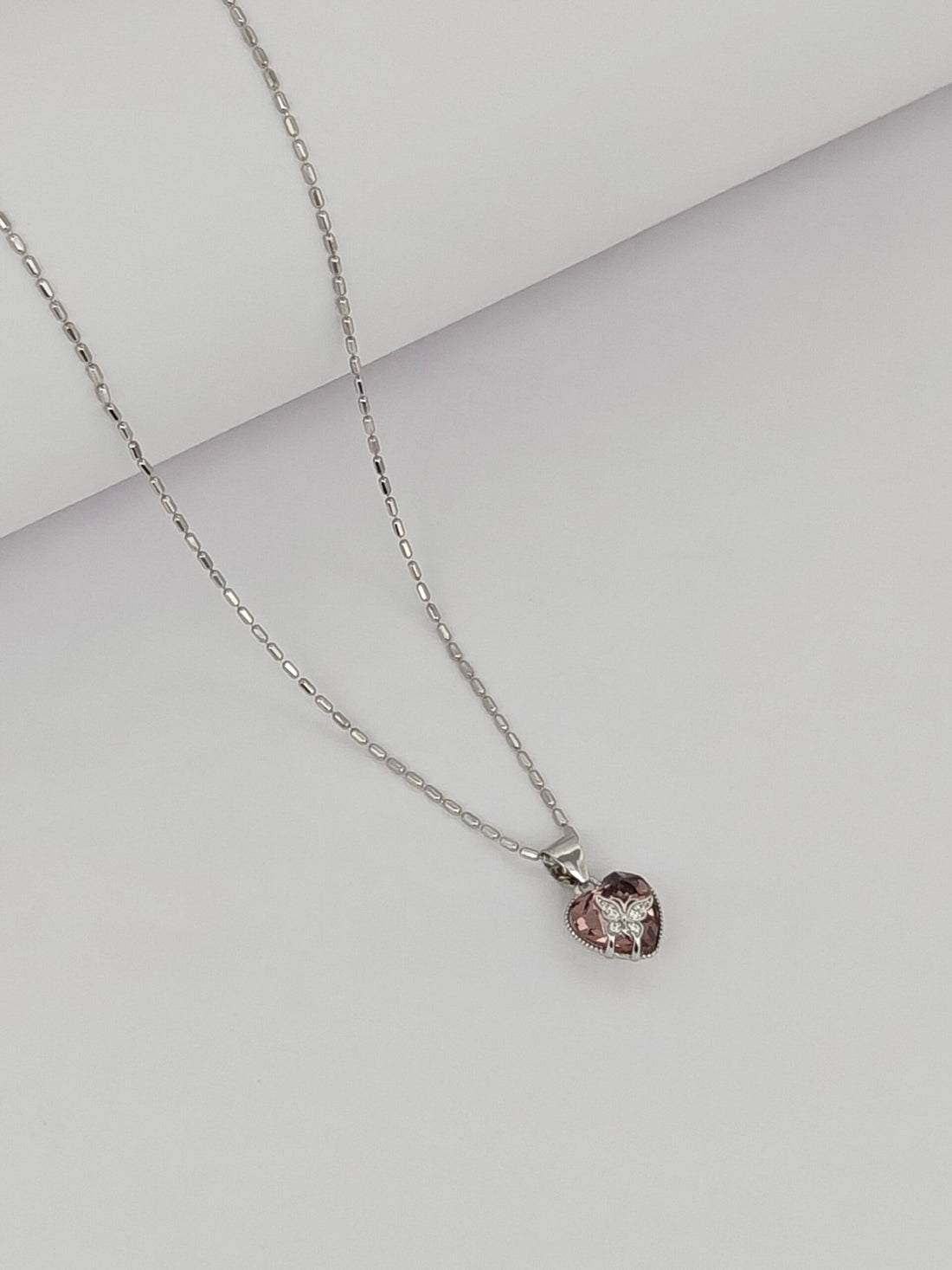 Necklace with a pink gemstone pendant on a light gray background