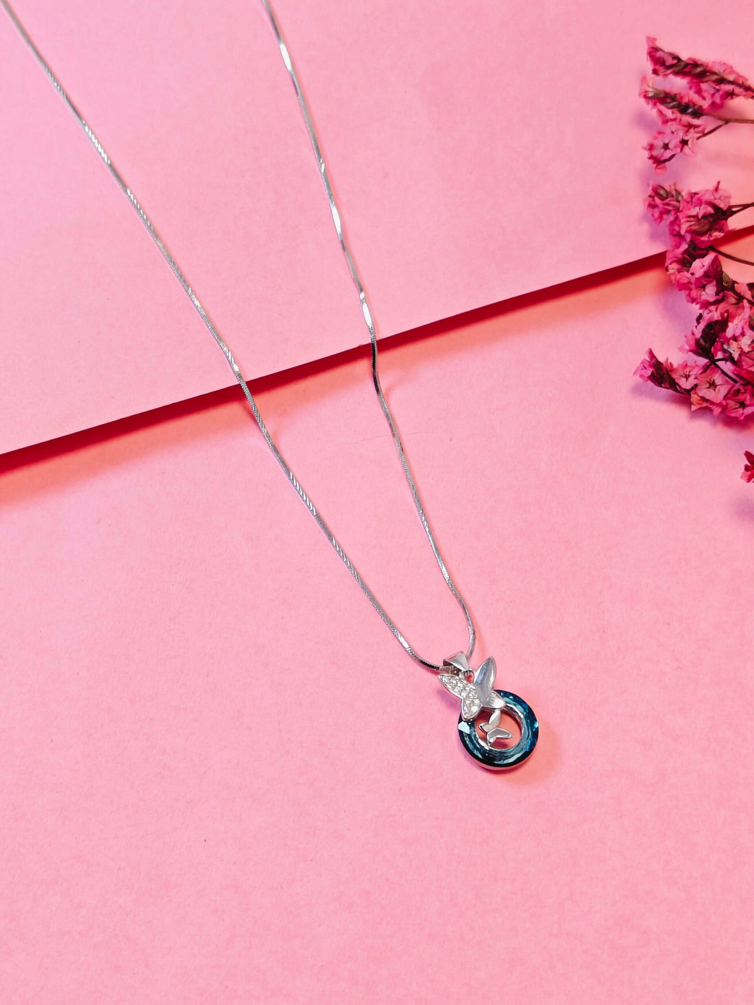 Silver necklace with a pendant on a pink background