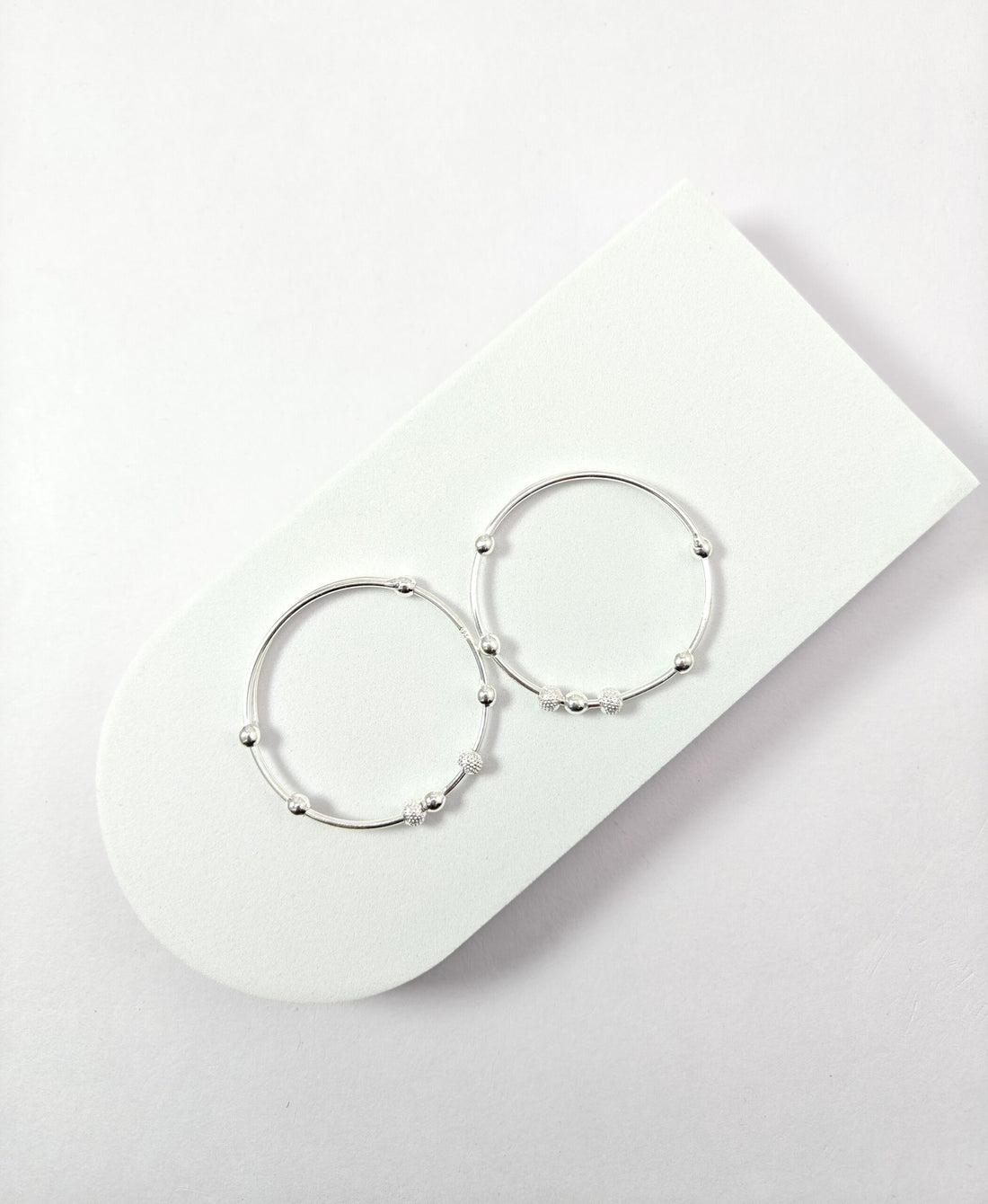 Pair of silver hoop earrings on a white surface