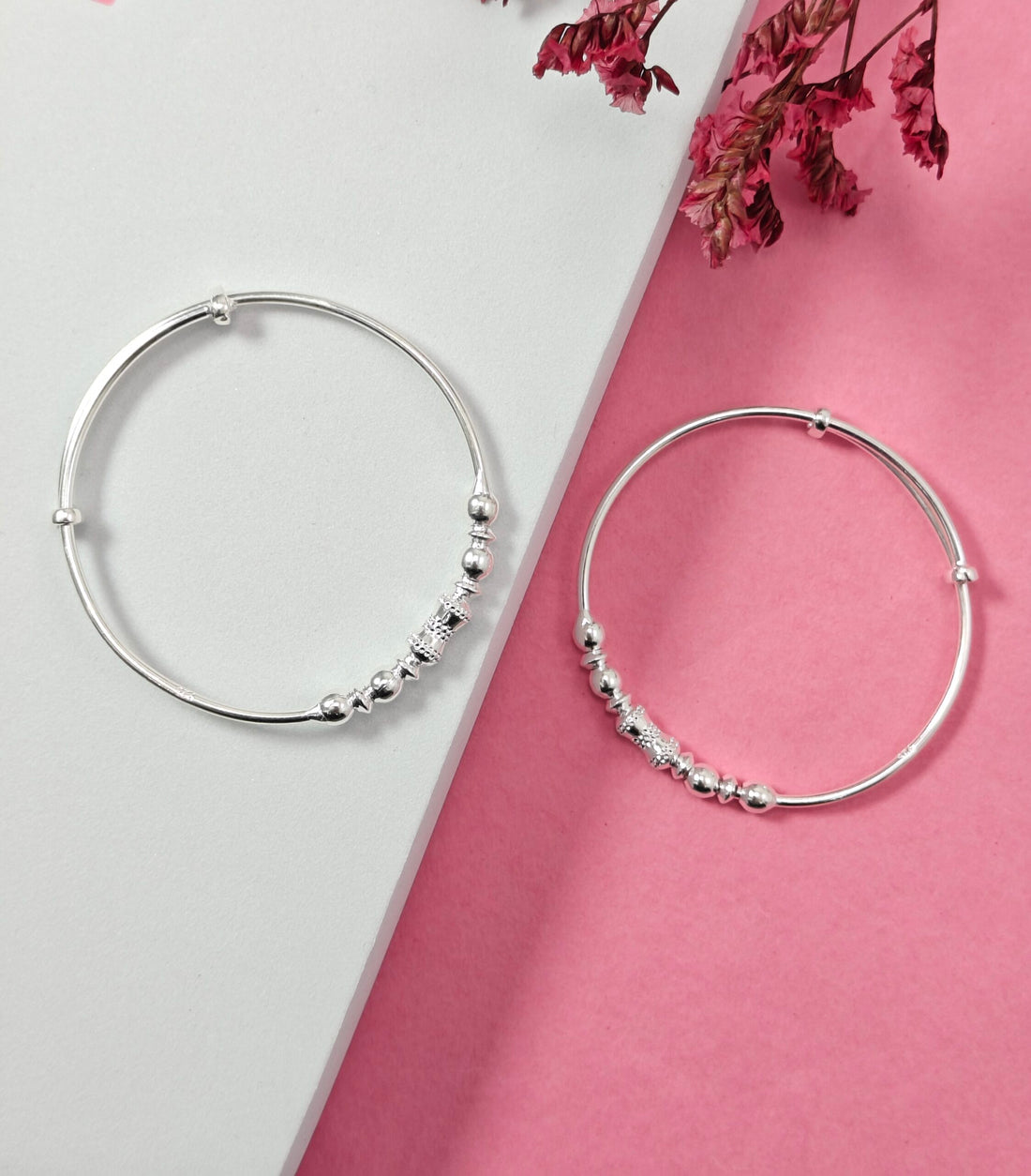 Silver hoop earrings with bead detailing on a pink and white background
