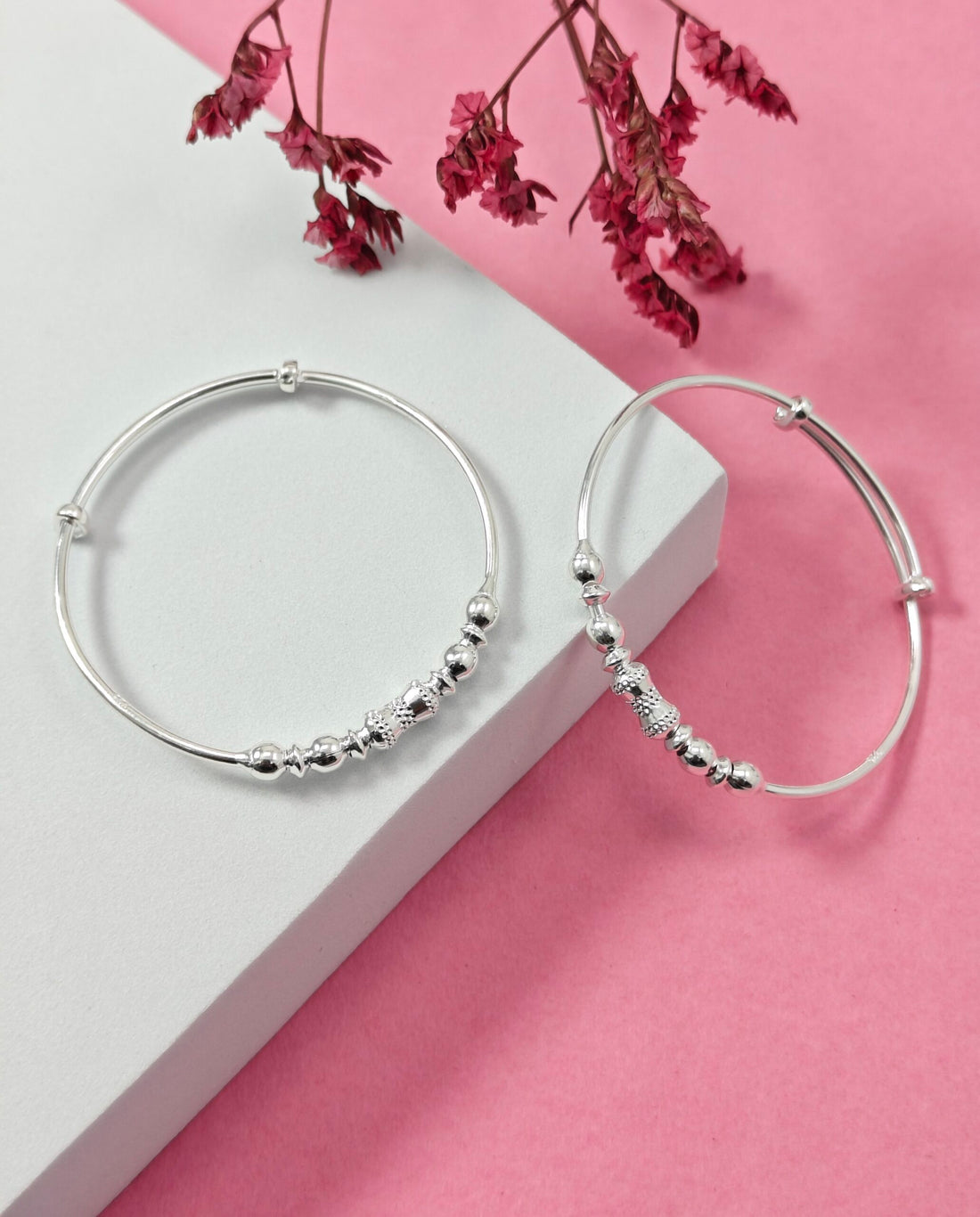 Silver hoop earrings on a pink and white background with cherry blossoms.