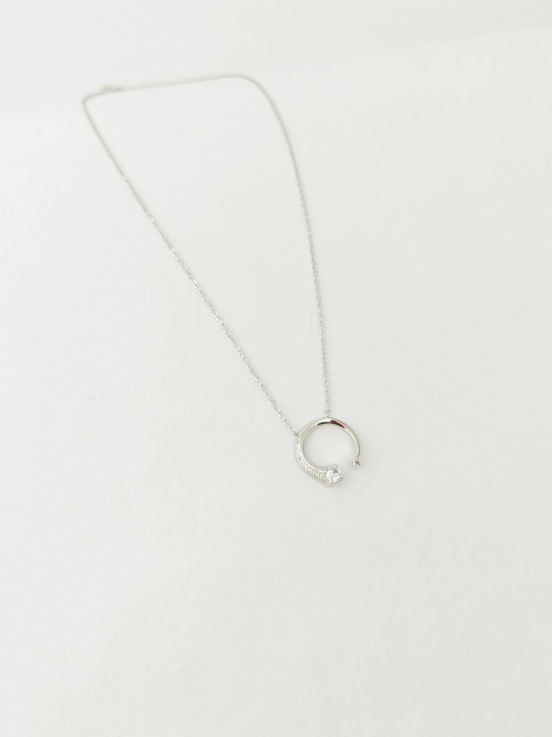Silver necklace with a circular pendant on a white background