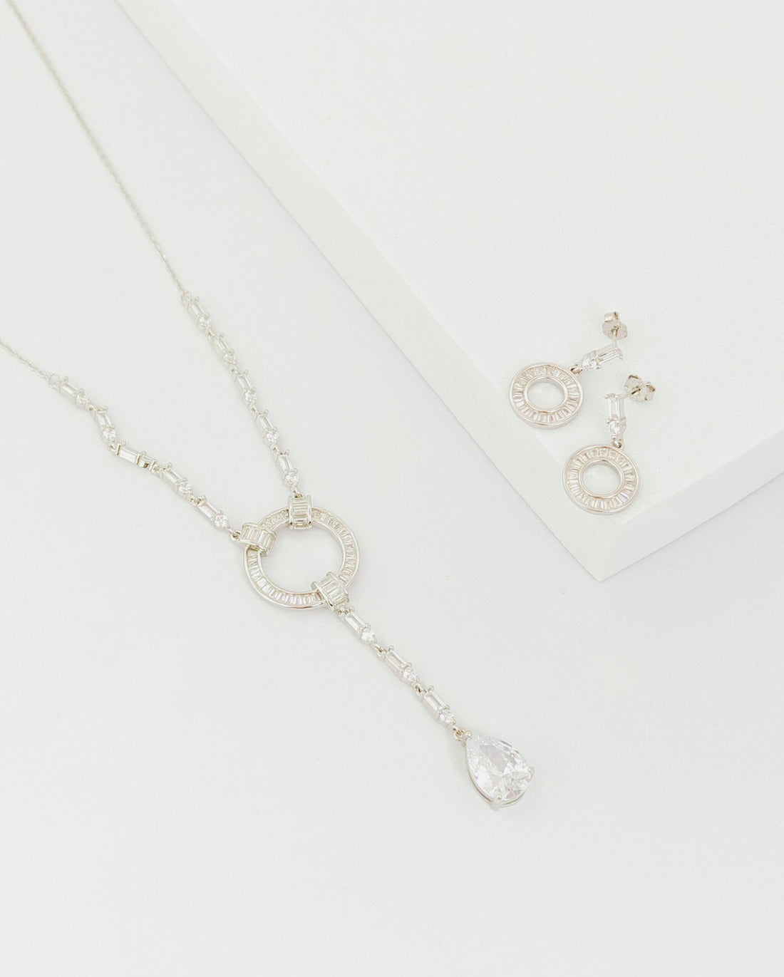 Silver necklace and earrings on a white background