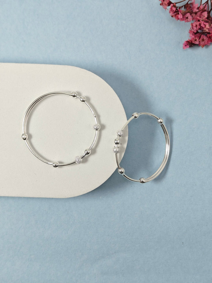 Silver hoop earrings on a light blue background with pink flowers.