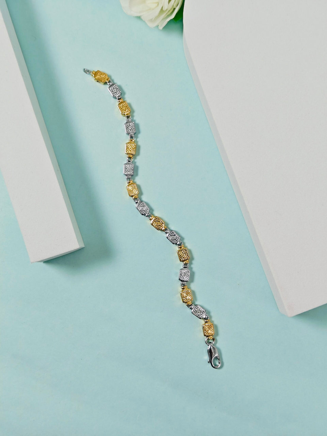 Bracelet with gold and silver beads on a light blue surface