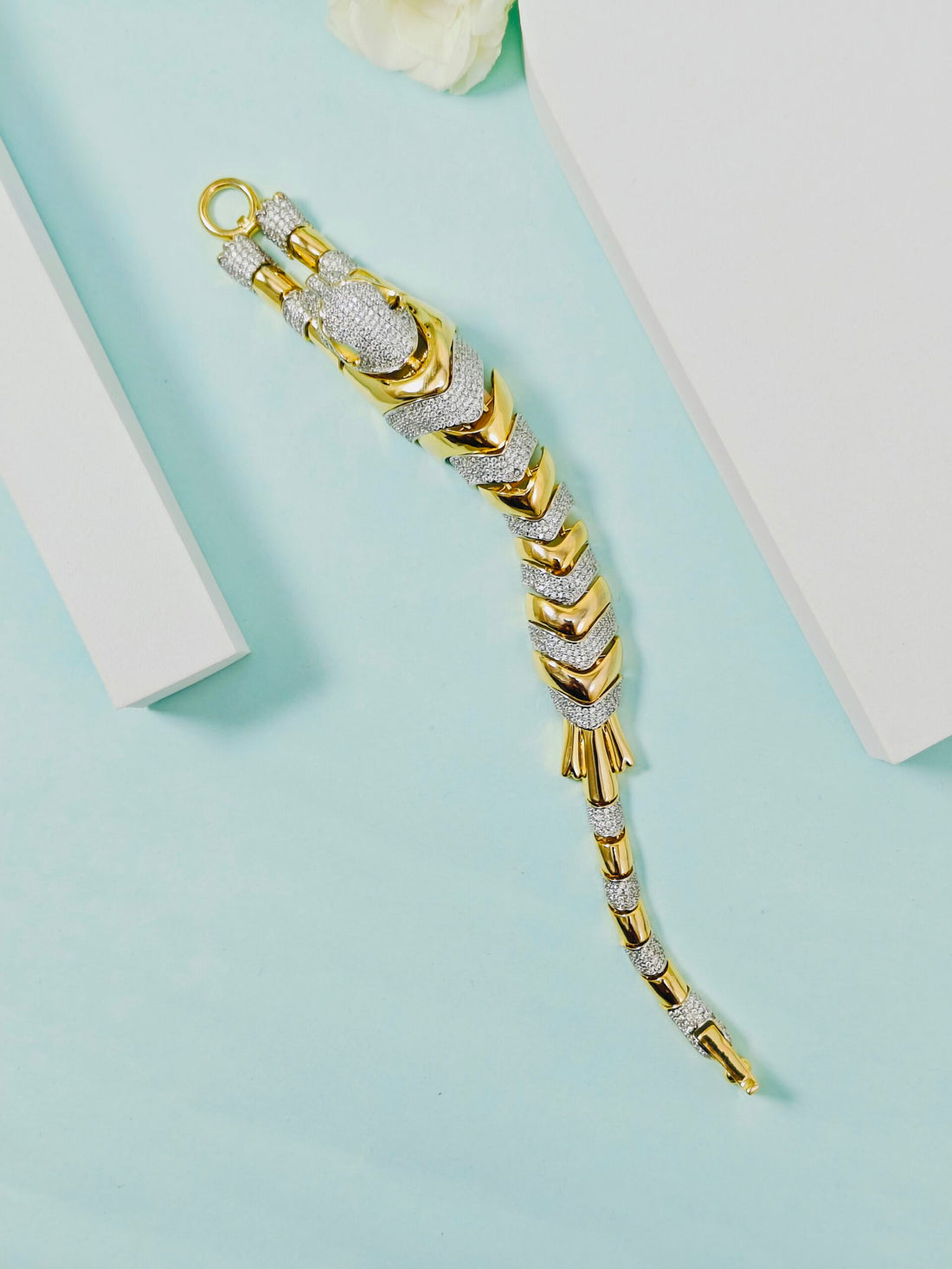 Gold and silver bracelet on a light blue background