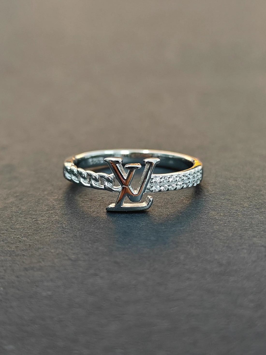 Silver ring with a prominent 'V' design on a dark surface