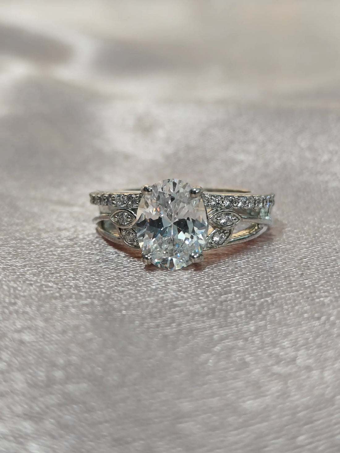 Silver ring with a large central gemstone on a textured gray surface