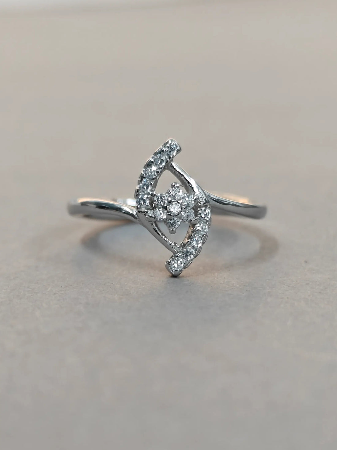 Silver ring with diamond accents on a light gray background