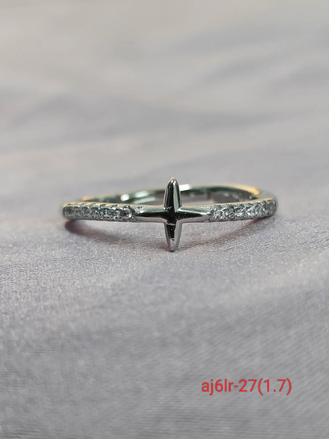 Silver ring with a cross design on a gray background