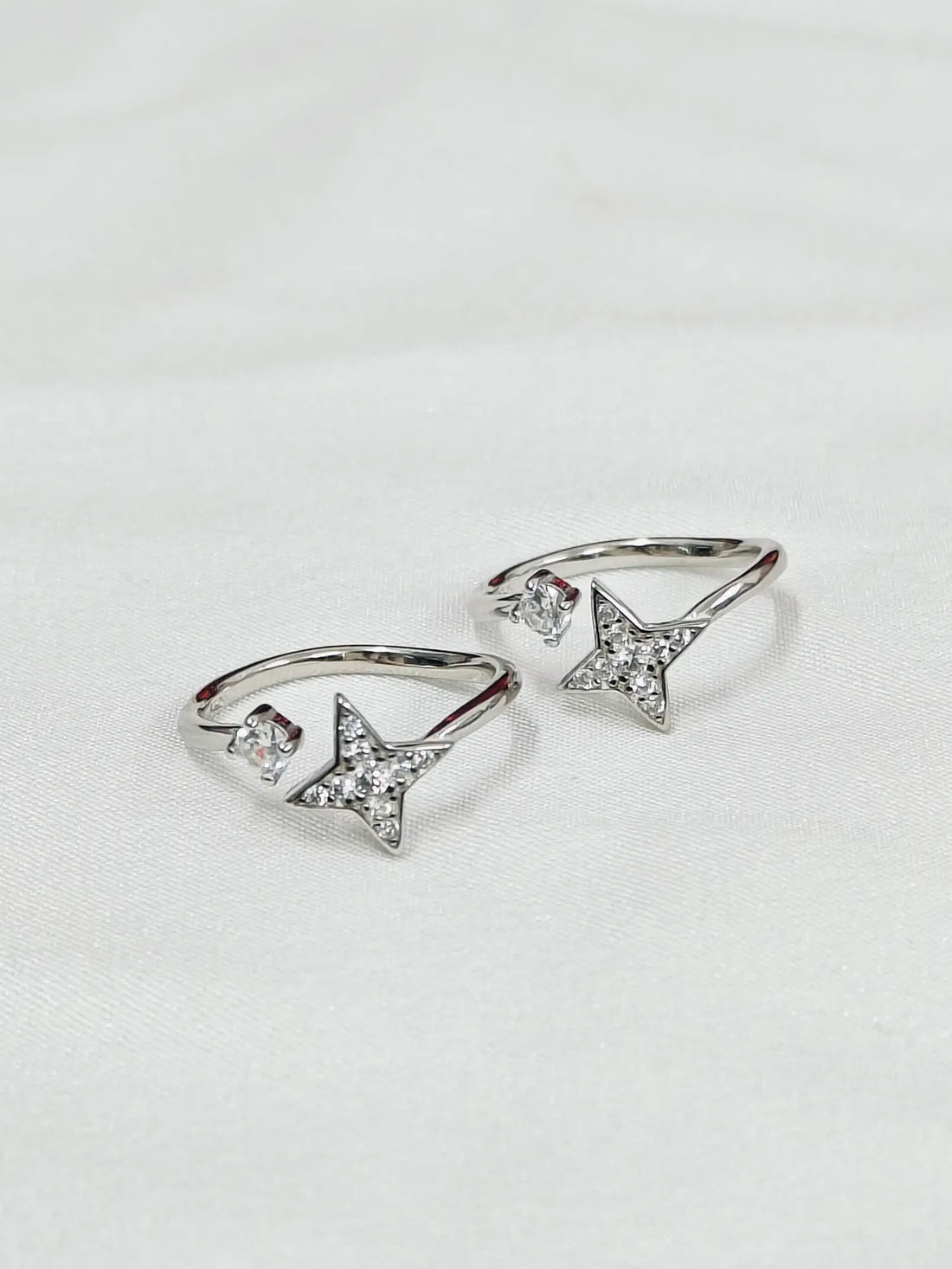 Silver star-shaped ring on a light gray background