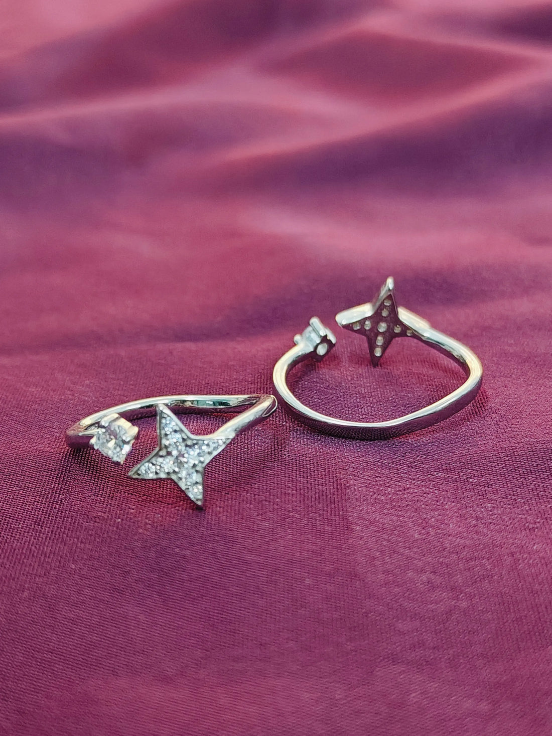 Two star-shaped rings on a purple fabric background