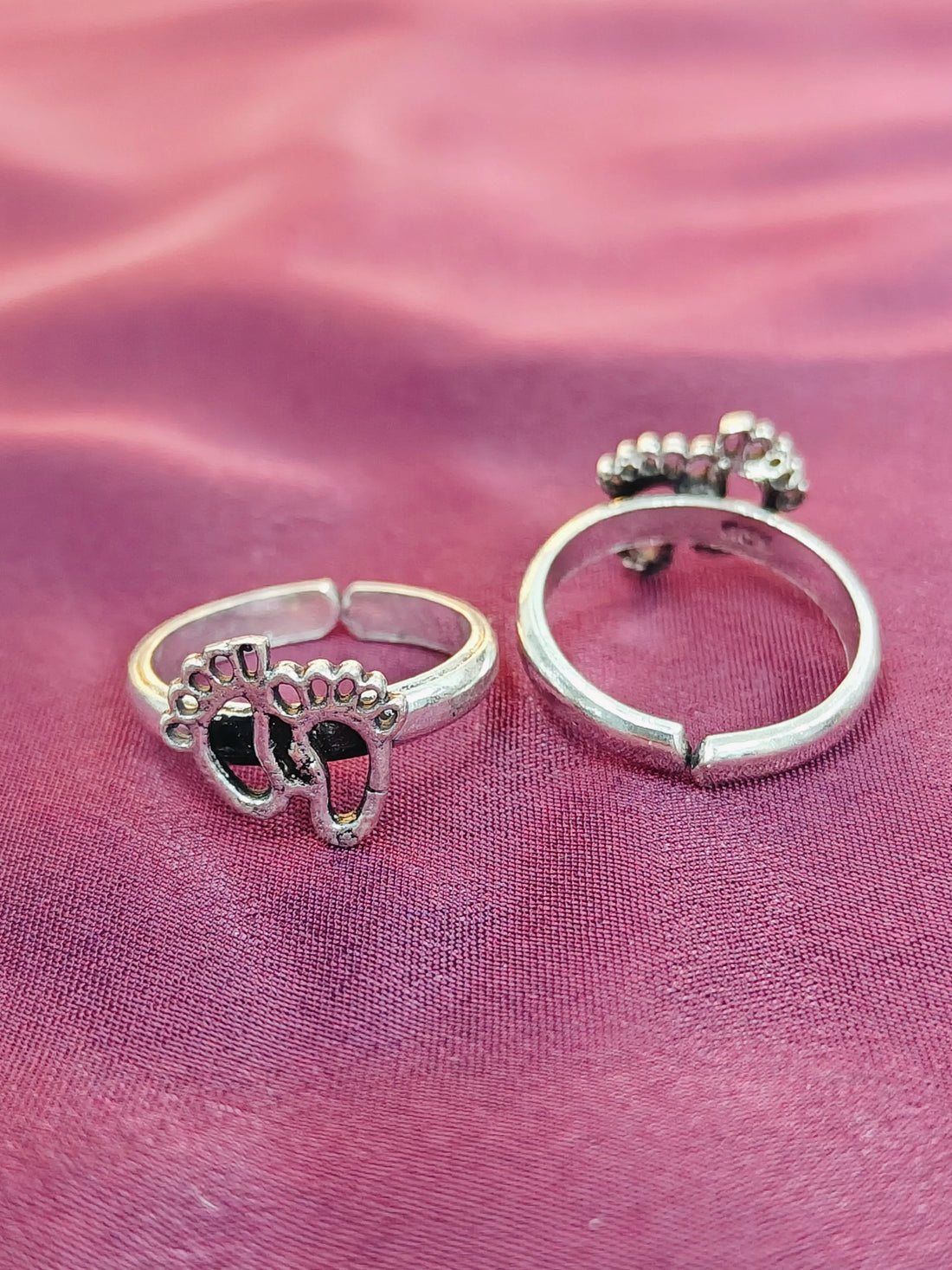 Two silver rings on a pink fabric background