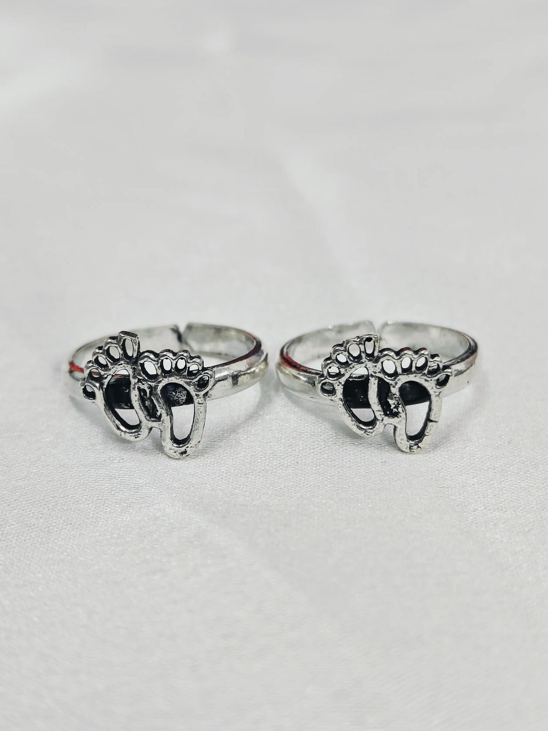Two silver rings with elephant designs on a light gray background