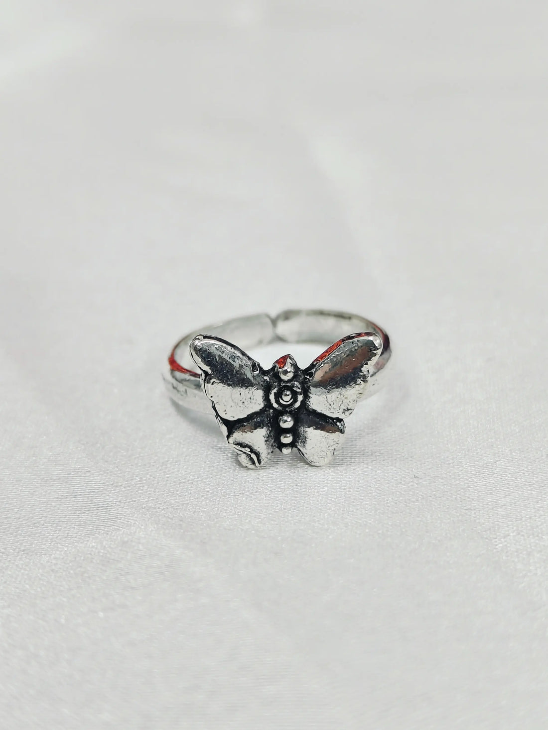 Silver butterfly ring on a light gray background