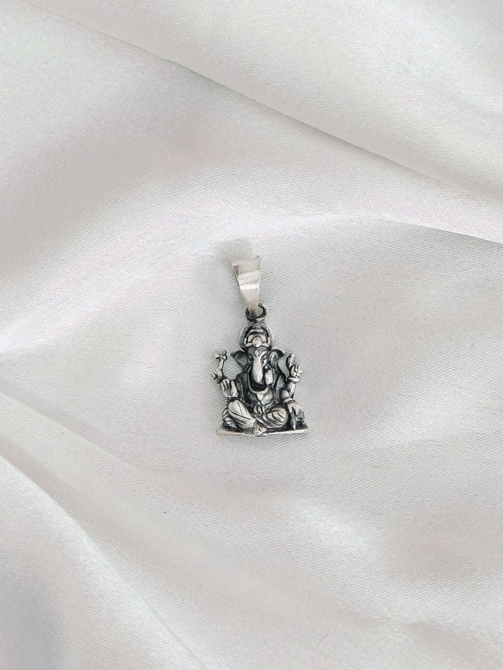 Silver pendant of a deity figure on a white satin background
