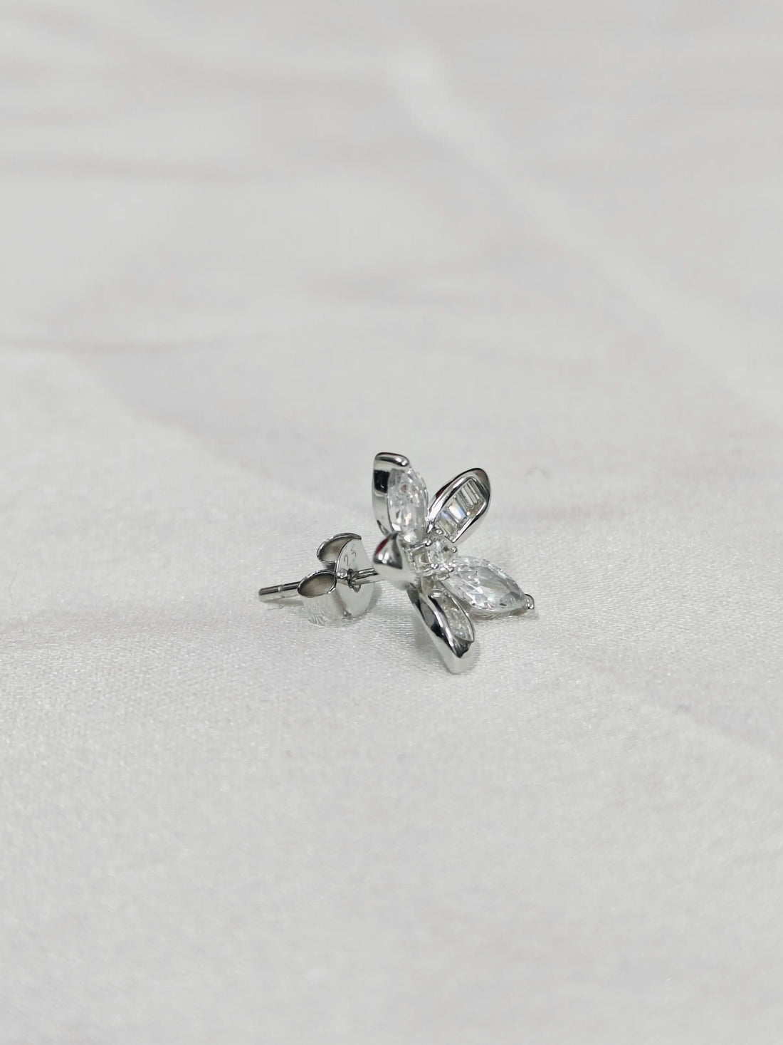 Silver butterfly-shaped earring on a light gray background