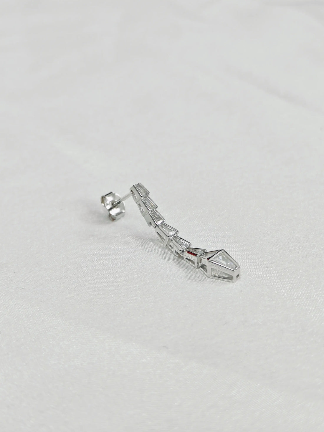 Silver earring on a light gray background