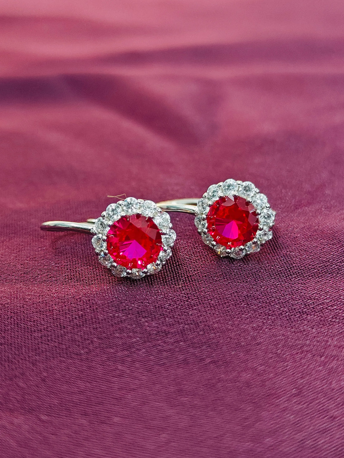 Pair of earrings with red gemstones on a purple fabric background