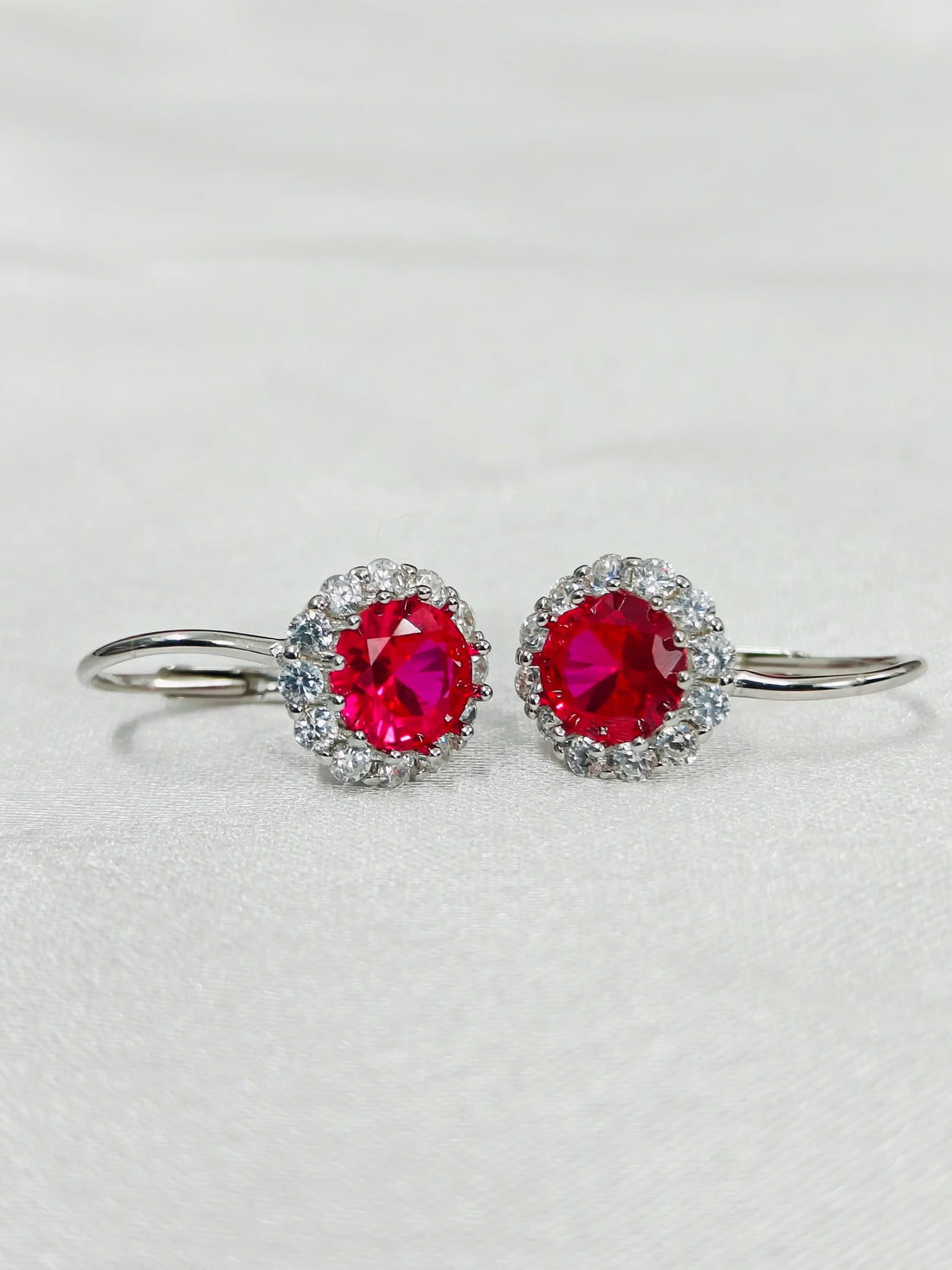 Pair of earrings with red gemstones on a light gray background