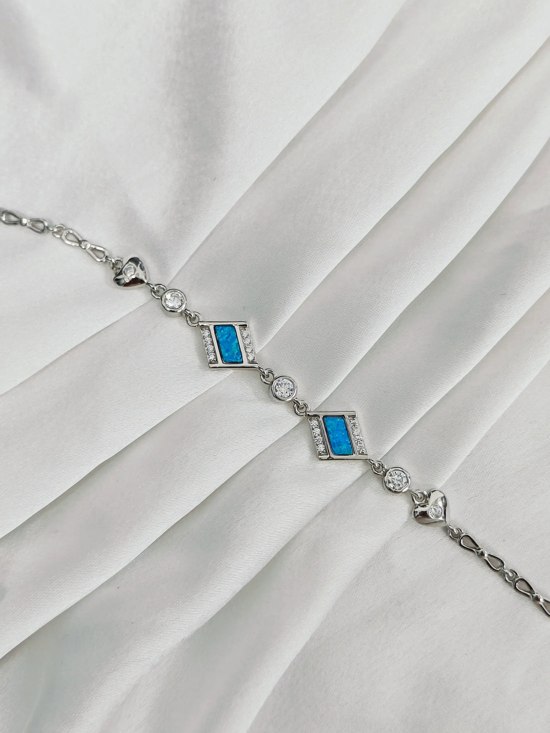 Silver bracelet with blue stones on a white fabric background