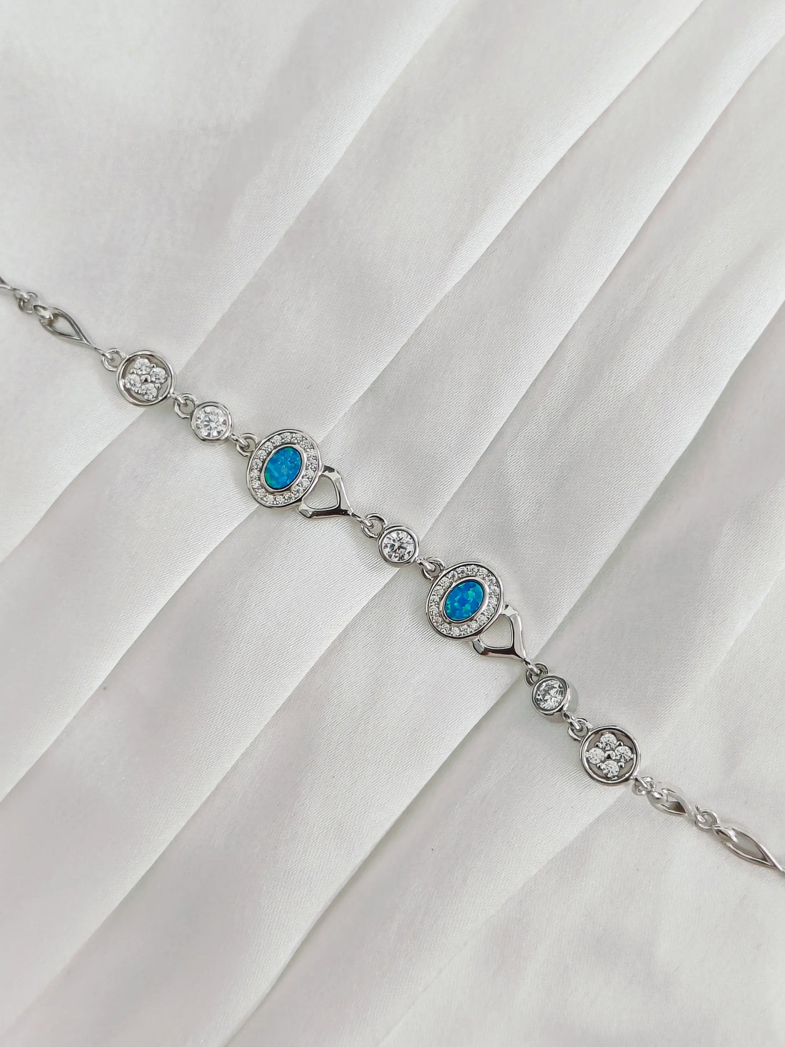 Silver bracelet with blue gemstones on a white fabric background