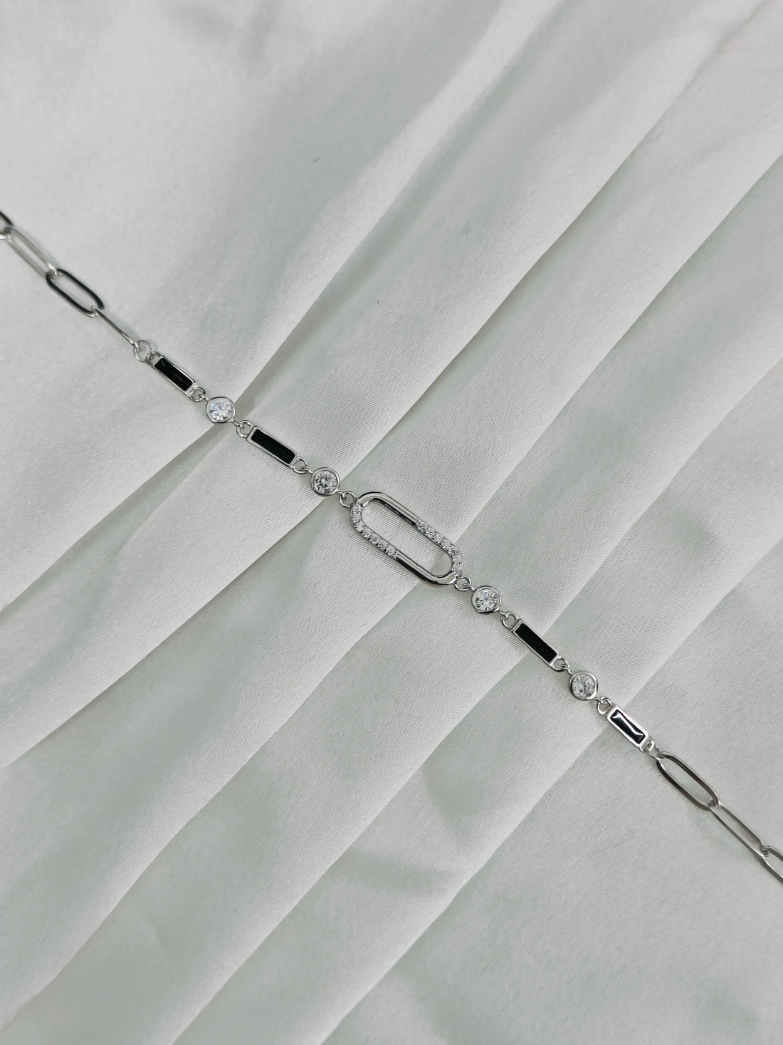 Silver bracelet with clear stones on a white fabric background