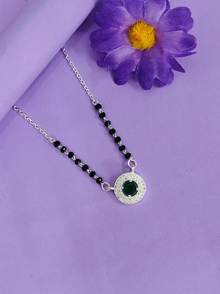 Necklace with a green pendant on a purple background with a purple flower