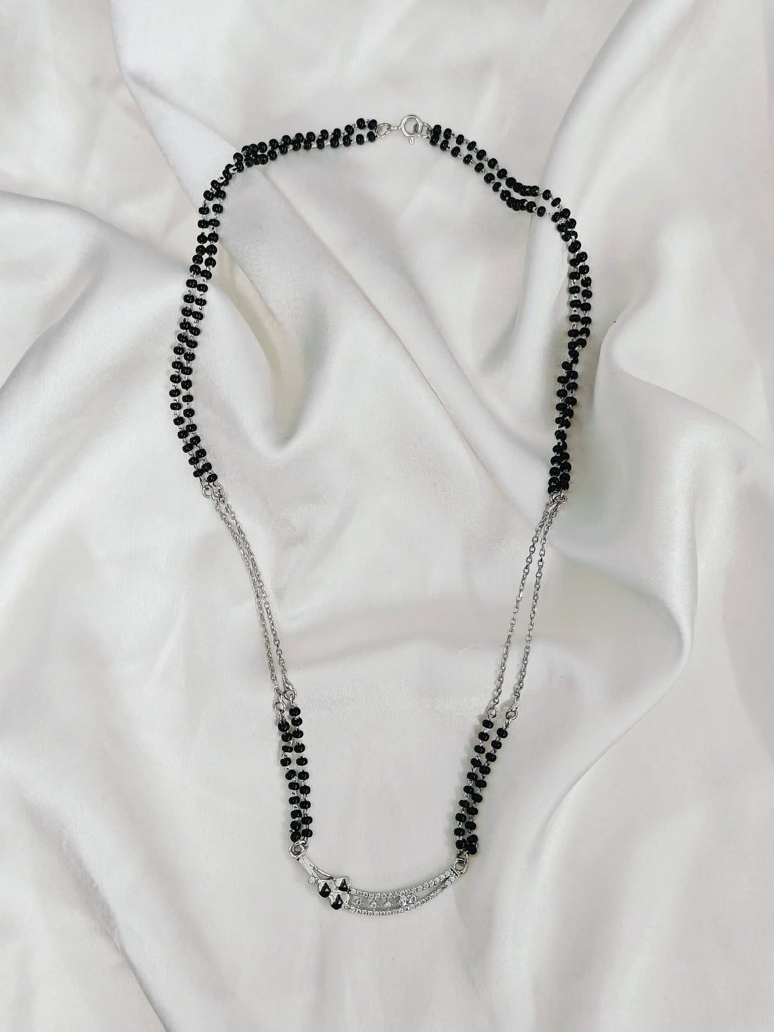 Necklace with black beads on a white fabric background