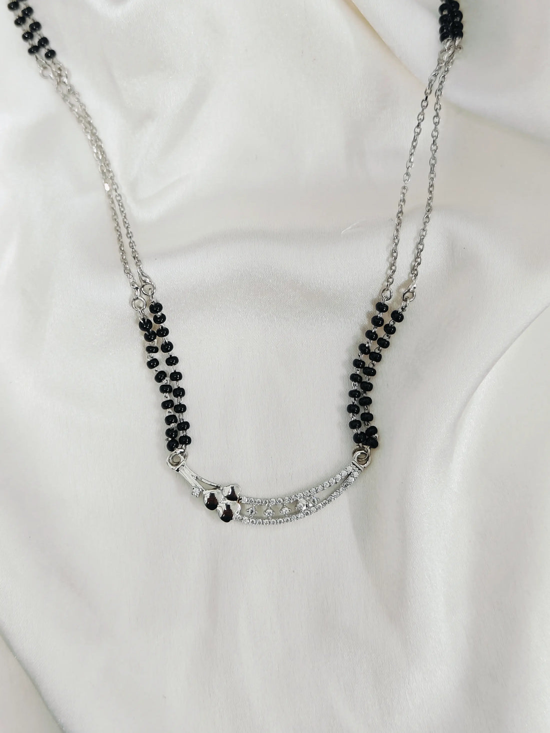 Necklace with black beads and silver chain on a white background