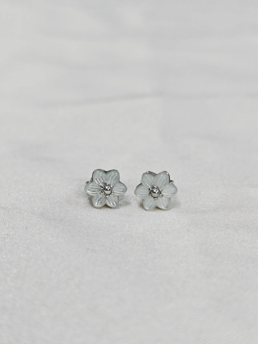 Flower-shaped earrings on a light gray background