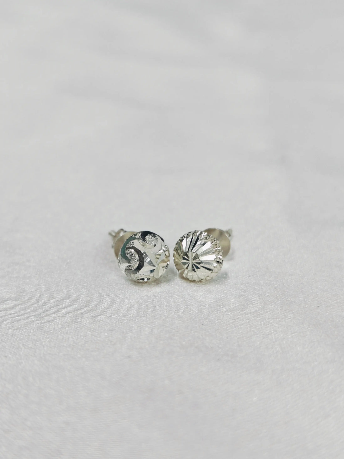Silver stud earrings with clear gemstones on a light gray background