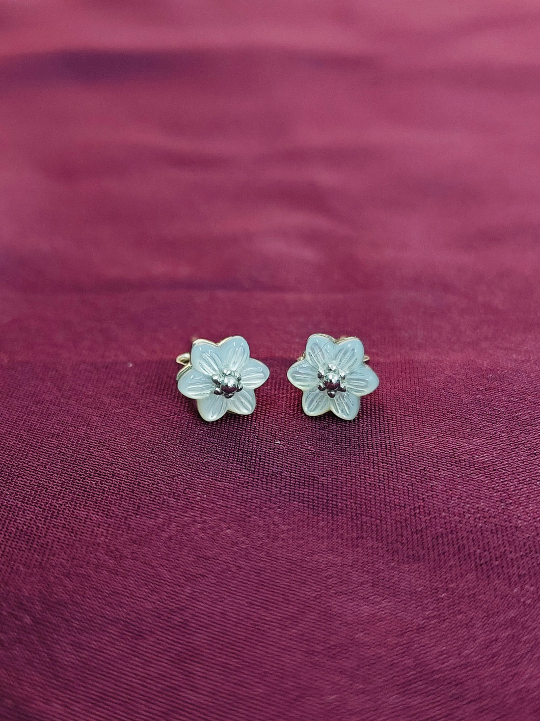 Flower-shaped earrings on a purple fabric background