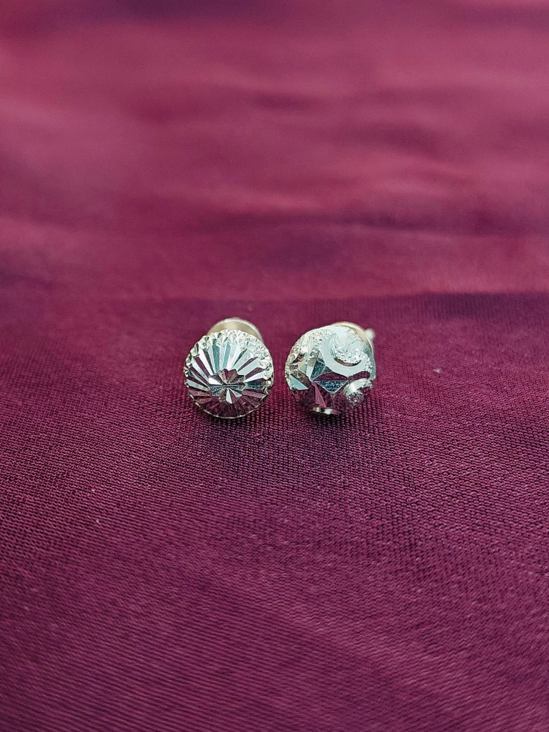 Silver shell-shaped earrings on a purple fabric background
