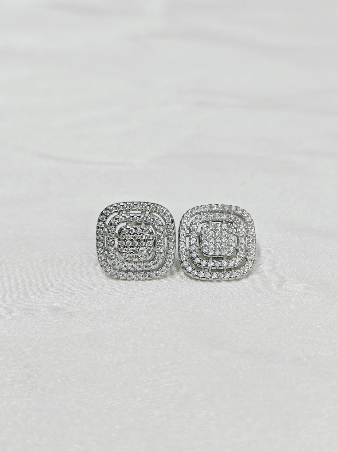 Silver square earrings with clear stones on a light gray background