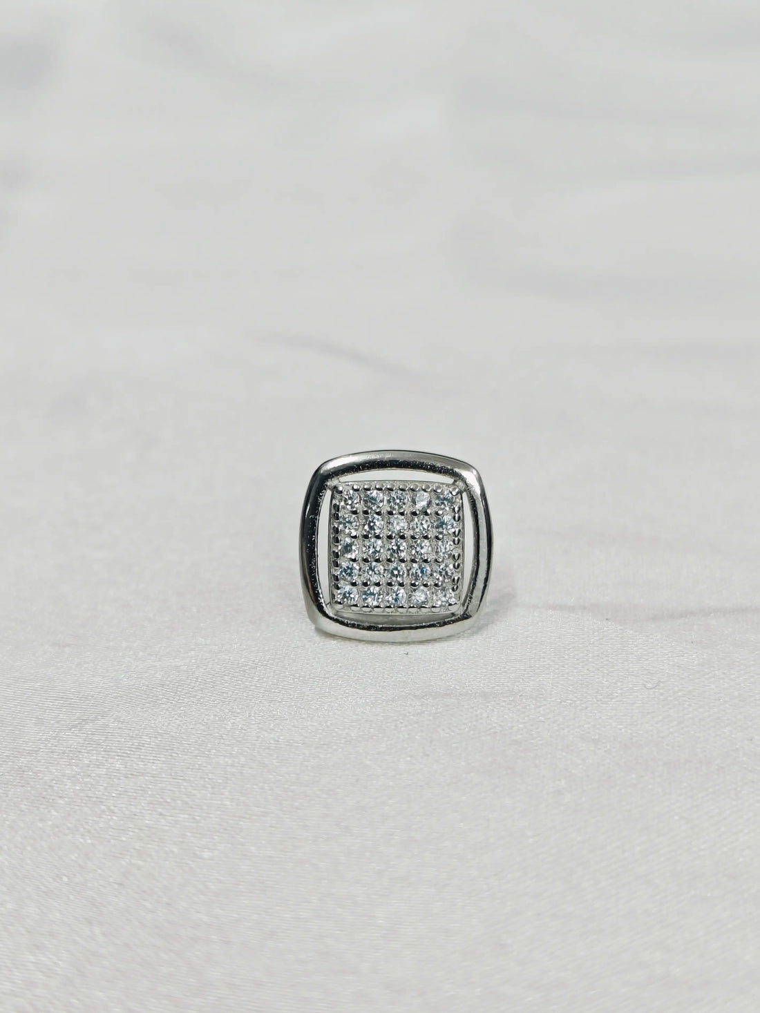 Silver ring with embedded stones on a light gray background