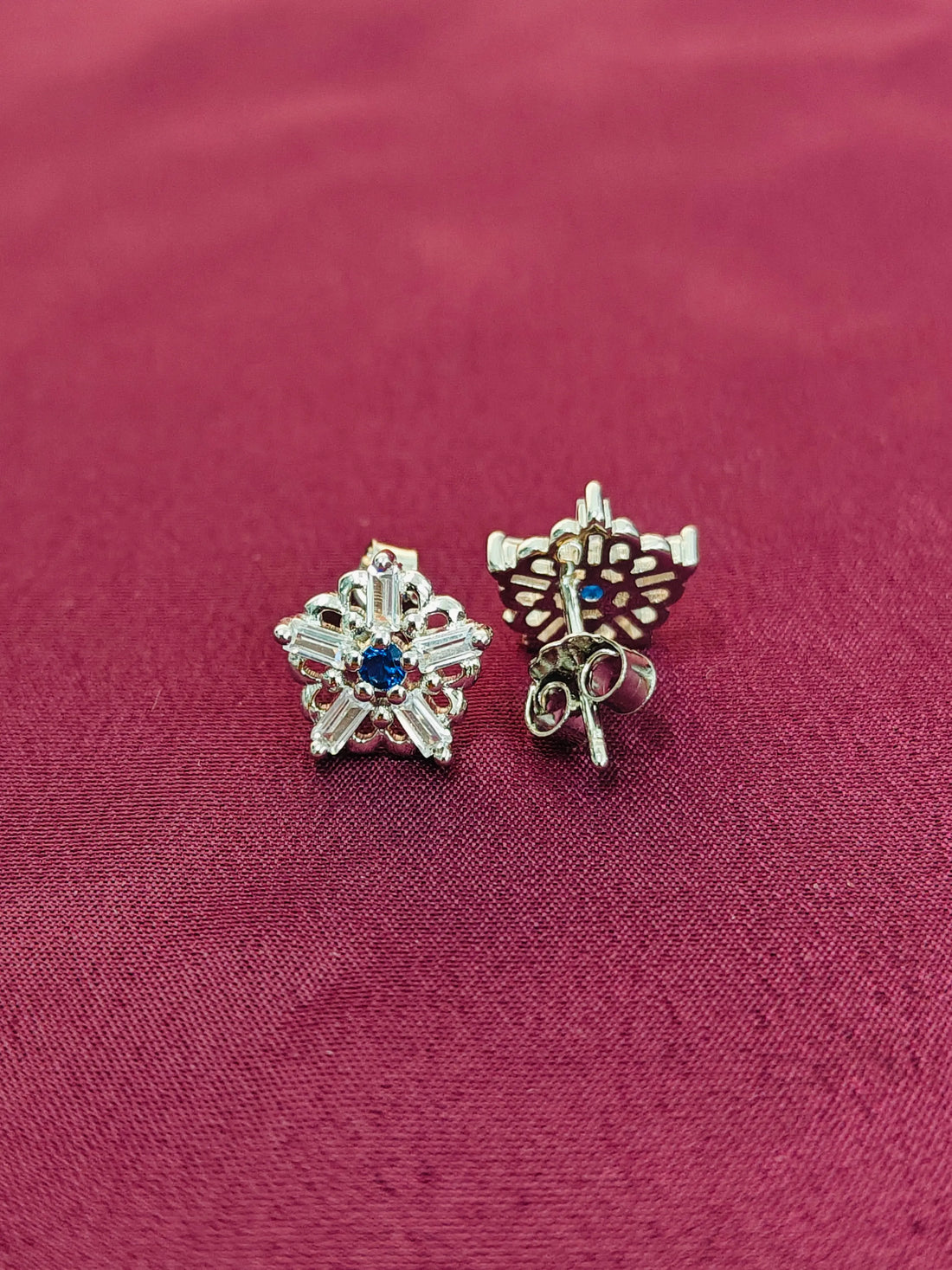 Pair of silver earrings with gemstones on a red fabric background