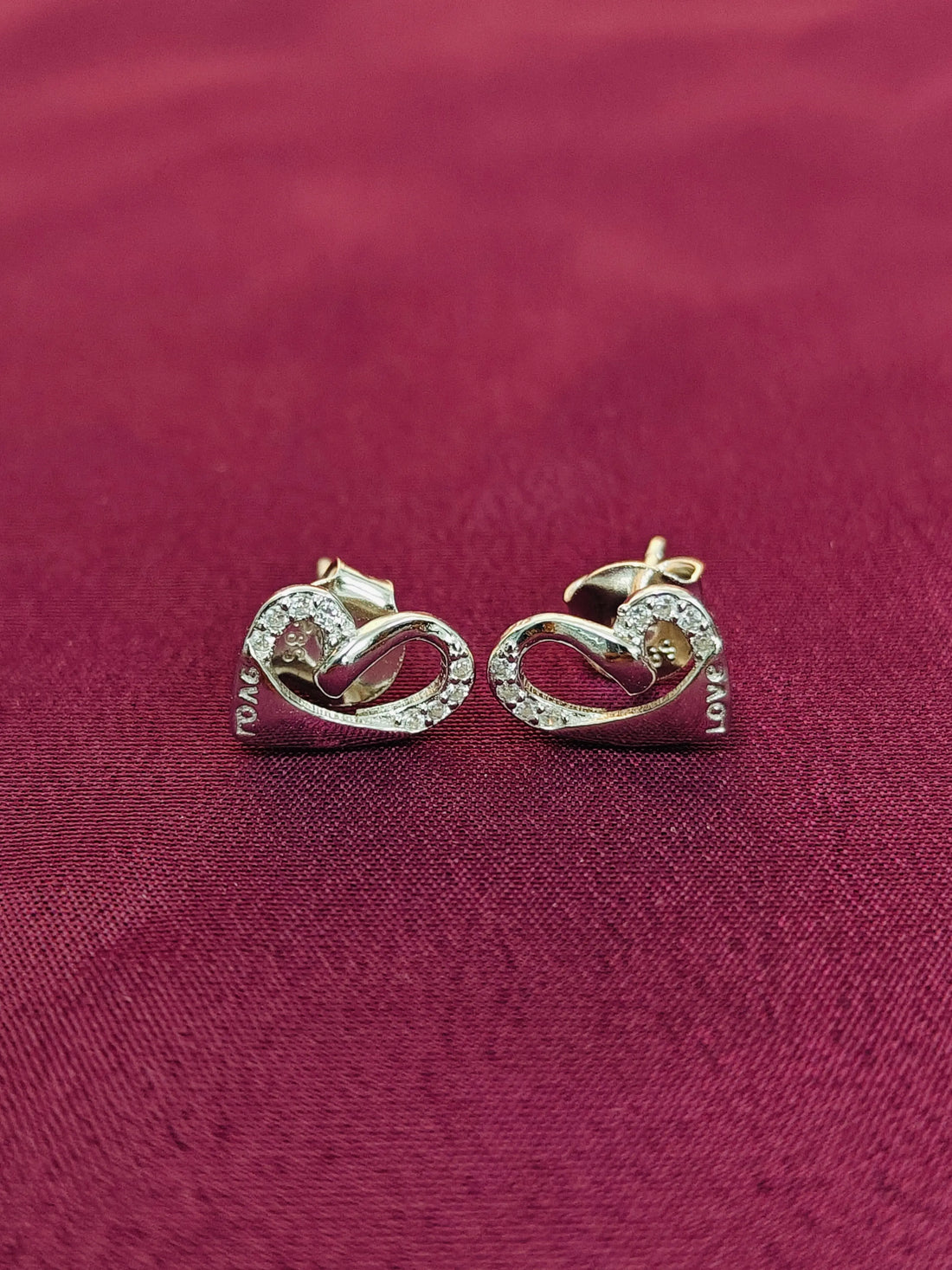 Pair of gold earrings on a red fabric background