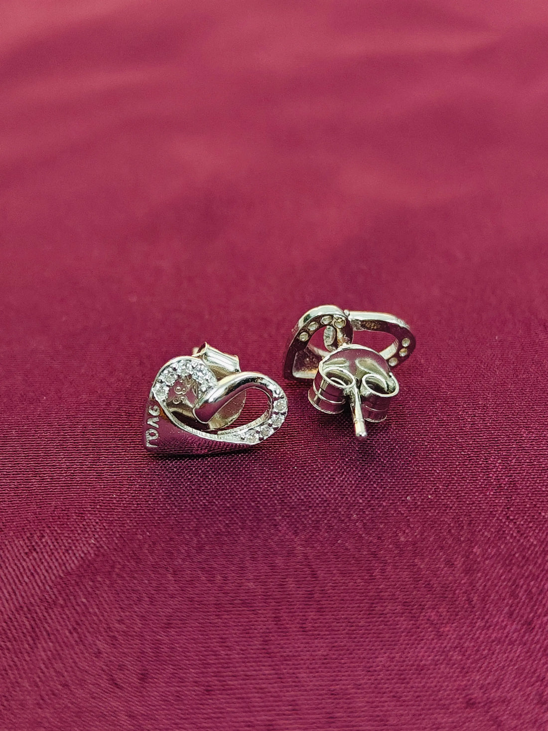 Pair of silver earrings on a red fabric background