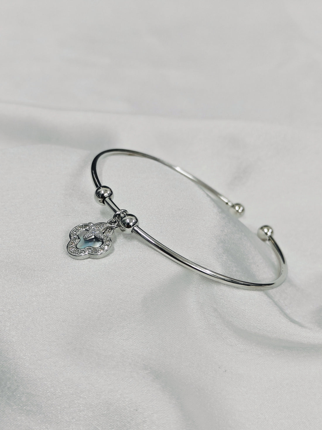 Silver bracelet with a heart-shaped charm on a white fabric background