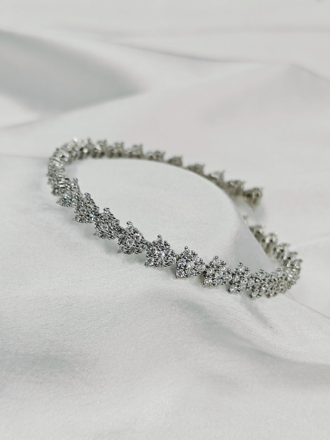 Silver bracelet with clear stones on a white fabric background