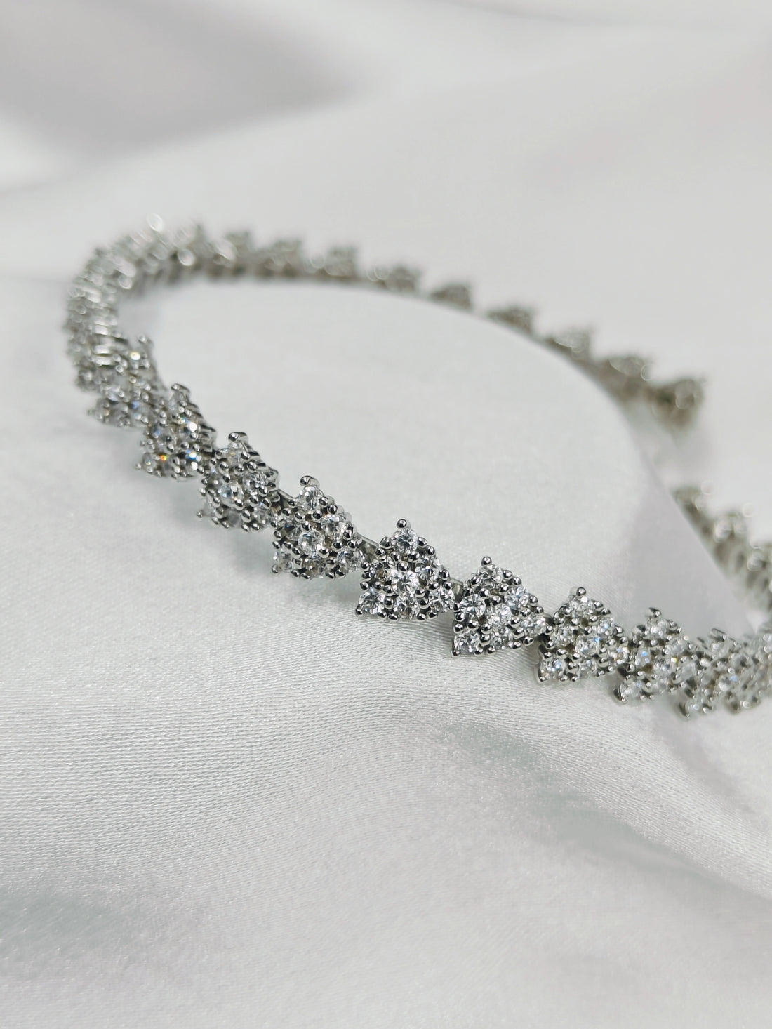 Silver bracelet with clear stones on a white fabric background