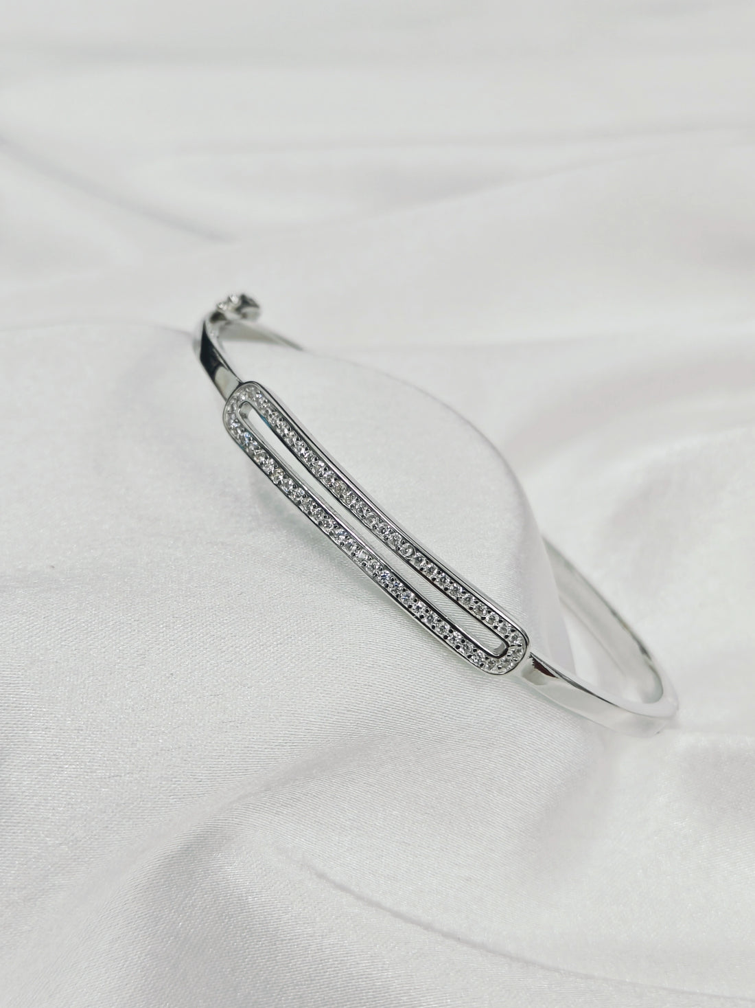 Silver bracelet with small stones on a white fabric background